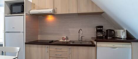 A compact kitchen with a microwave, stove, sink, and coffee maker.