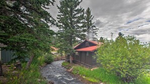 Une cabane située au bord d’un ruisseau, entourée d’une forêt dense.
