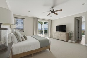 A bedroom with a bed, a TV, a ceiling fan, a window with curtains, and a view of palm trees. - Temecula Wine Country Retreat - Pool, Spa, Stunning Views & Minutes to Wineries! (Temecula)