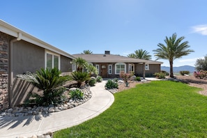 A house with a curved driveway, palm trees, and a well-maintained lawn.