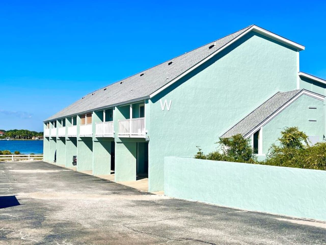 A light blue building with a balcony, a 'W' on the side, and a view of the sea.
