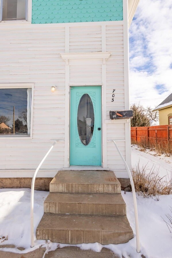 Une maison avec une porte turquoise, une boîte aux lettres et le numéro 703 peint sur le mur.