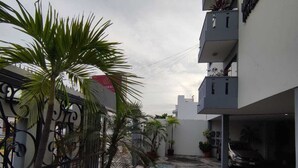 Ein Hotel mit Eingangsbereich, befestigter Auffahrt, Palmen und einem Parkplatz.
