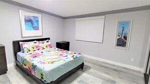 Een slaapkamer met een bed, een kaptafel, nachtkastjes en kunstwerken aan de wanden.