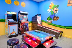 A room with arcade games, a Mario-themed mural, and a ping pong table. - Epic 9BR Game House - Arcade, PS5, Pool & Hot Tub (Davenport)