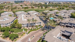 Una zona residencial con casas modernas, una avenida central y un campo de golf.