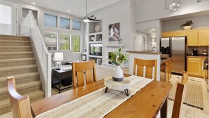 Una cocina moderna con refrigerador integrado, armarios de madera y un comedor con mesa y sillas de madera.