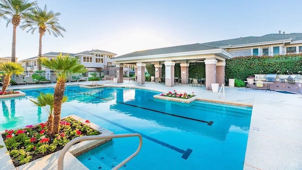 Una piscina con palmeras, un patio techado y un edificio con tejado de baldosas.