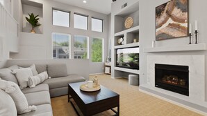 Una sala de estar moderna con un sofá gris, una mesa de centro oscura y una chimenea.