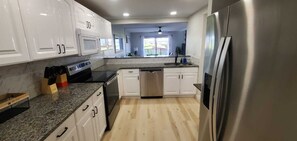 Una cocina moderna con armarios blancos, un refrigerador de acero inoxidable y un lavavajillas.