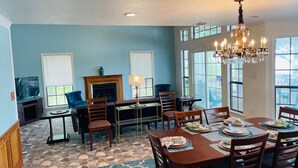 A dining area with a stone floor, wooden furniture, and a chandelier. - Waterfront, Boat Dock, Great Fishing - Long Term Renters Welcome - Sleeps 9 (Trinity)
