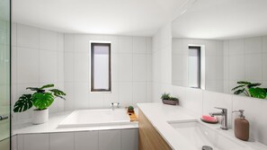 A modern bathroom with white tiles, a large window, and two sinks. - Oogarding Unit 14, 46 Warne Tce (Kings Beach)