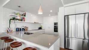 A modern kitchen with a central island, stainless steel appliances, and a hanging pendant light.