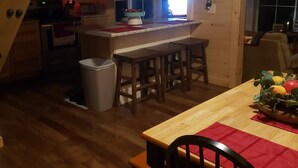 Een gezellige keuken met houten kastjes, een eethoek met een tafel en stoelen, en een bordje met de tekst 