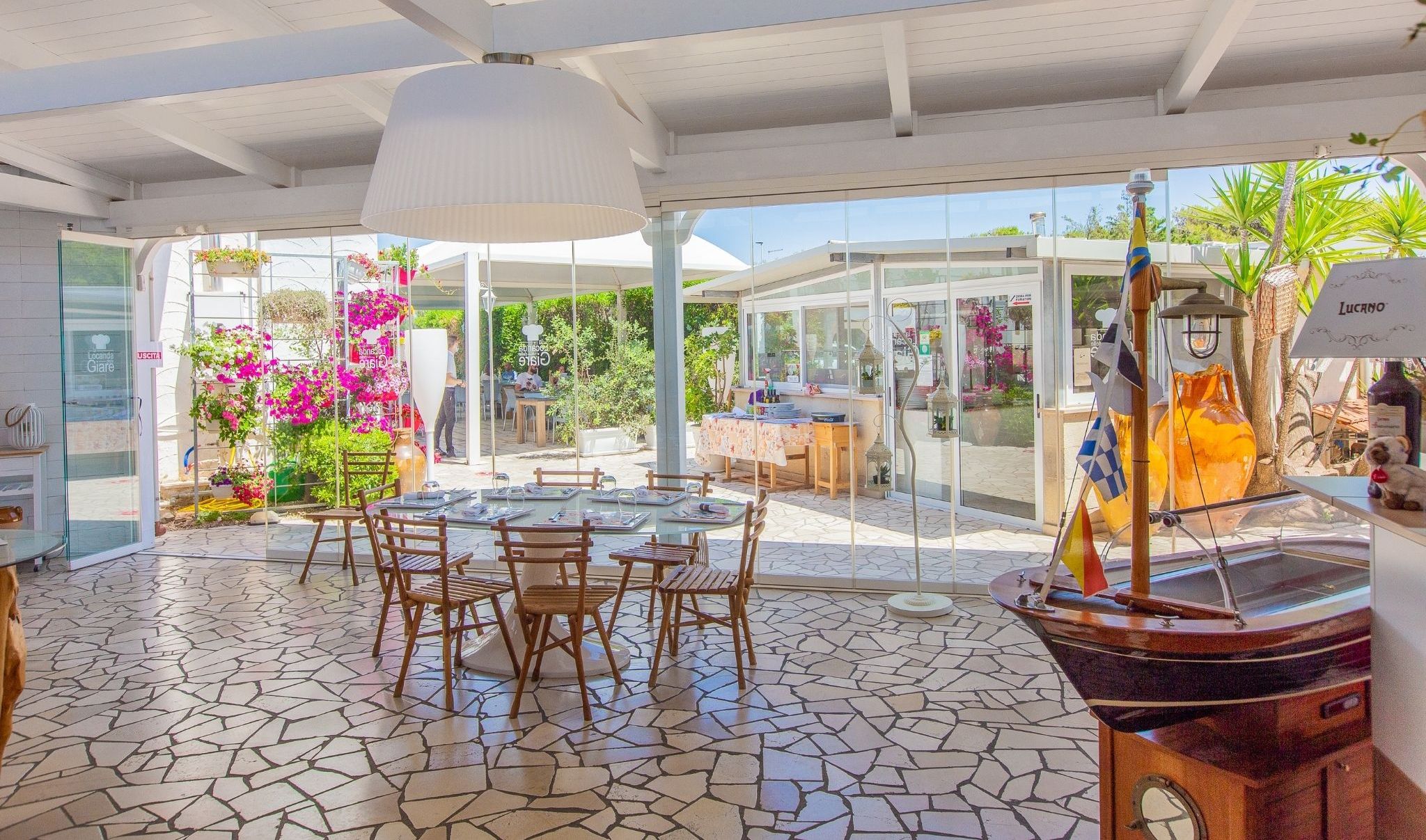 A restaurant with a glass enclosure, outdoor seating, and a ship model.