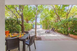 An outdoor dining area with a table set for a meal, surrounded by lush greenery and trees. - Family villa at 20 m from the sea - garden - laundry machine - 6 beds (Carovigno)