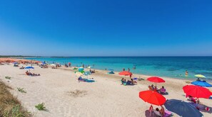 A beach with numerous colorful umbrellas and people relaxing on the sand. - Ground floor - private garden - 20 m from the beaches (Carovigno)