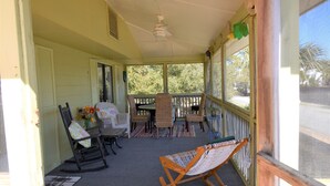 A covered porch with wicker furniture, a rocking chair, and a hammock.
