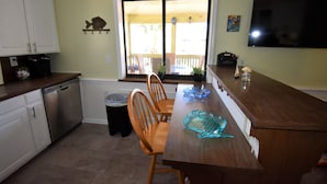 A kitchen with a dining table, chairs, a dishwasher, and a TV.
