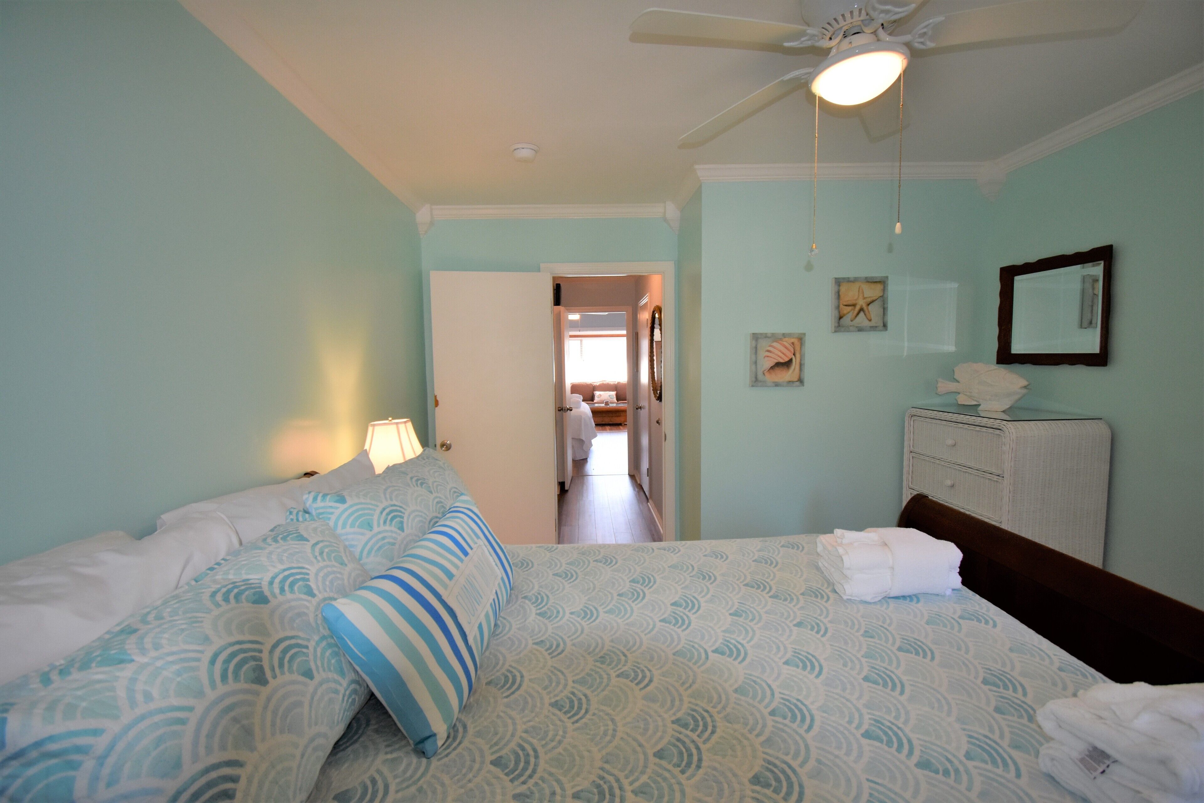 A bedroom with two beds, a ceiling fan, and a dresser.