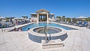 Un espace piscine avec des chaises longues et des parasols, un jacuzzi et un bâtiment portant l’inscription « KIVA BEACH CLUB ».