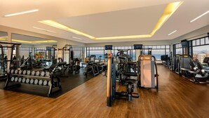 Ein modernes Fitnessstudio mit unterschiedlichen Trainingsgeräten, großen Fenstern und Holzboden.