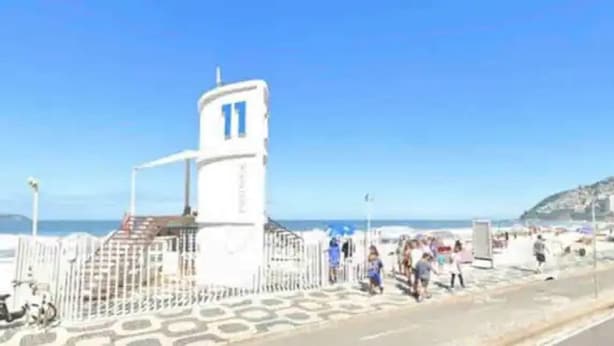 Une route côtière bordée d’un bâtiment blanc, doté d’une fenêtre bleue et d’une tour.