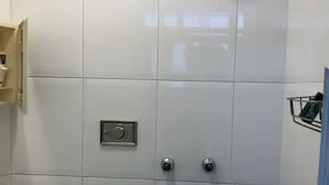 Une salle de bain avec un lavabo blanc, une douche et des toilettes.