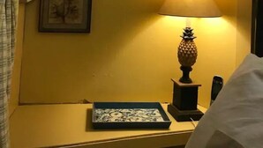 Une chambre d’hôtel avec un lit, une table de chevet avec une lampe et des tableaux encadrés au mur.