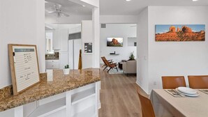 A modern kitchen with white cabinets, a granite countertop, and a dining area with a table set for two.