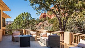 An outdoor patio with wicker furniture, a table, and a view of red rock formations.