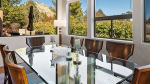 A dining area with a glass table, wooden chairs, and a view of trees and mountains. - Lux 2-King Suite Luxury Townhome! Pool + Hot Tub! (Sedona)