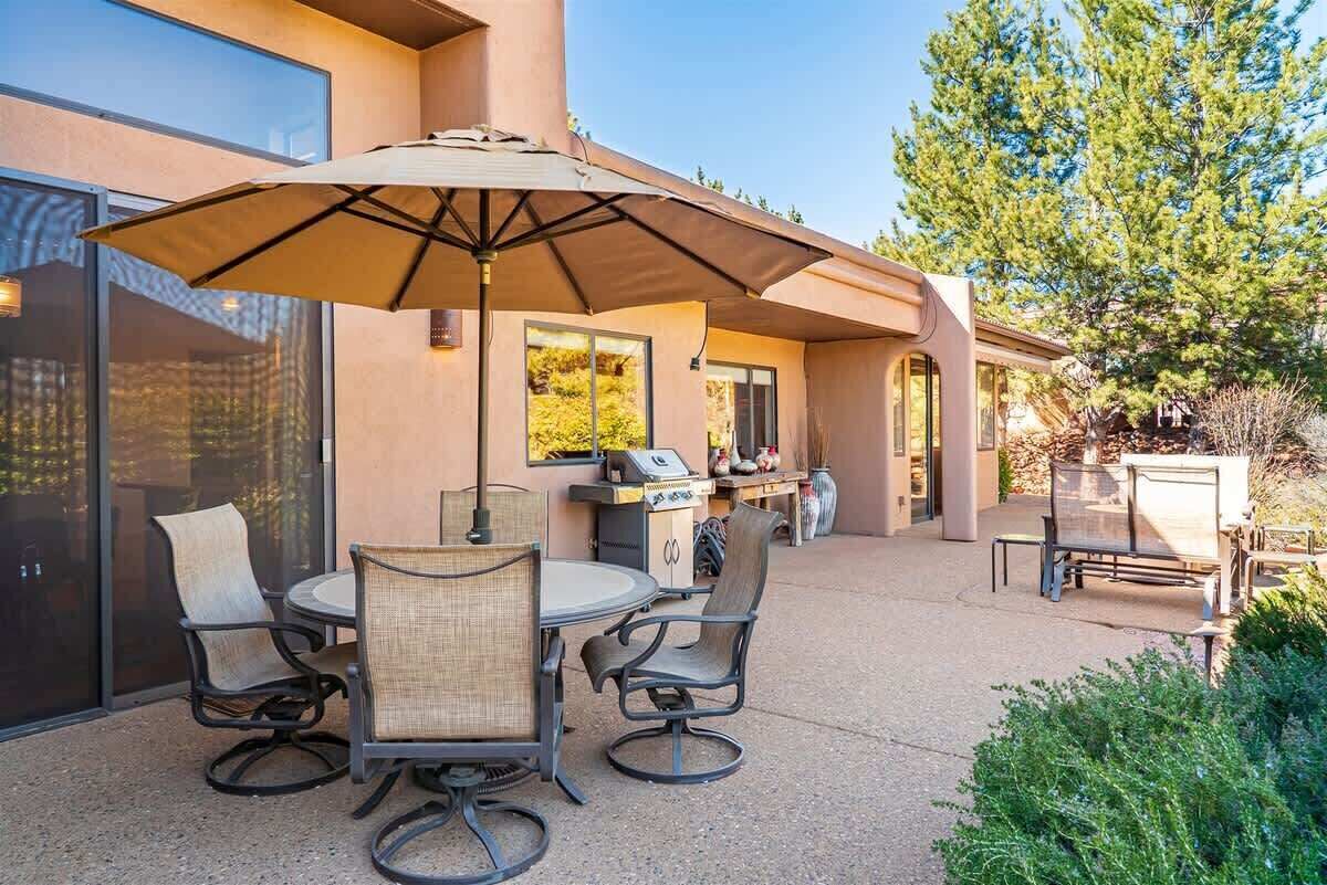 An outdoor patio with a round table, chairs, and a large umbrella.