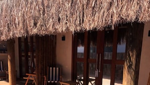 A pool area with a thatched roof, wooden deck, and tiled pool.