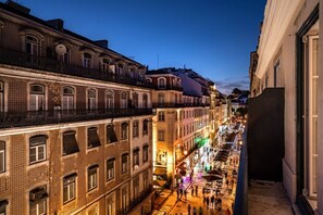 A narrow street lined with historic buildings, featuring balconies and a bustling pedestrian area.