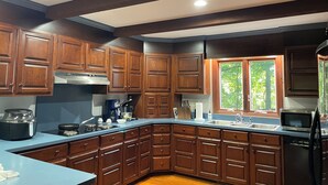Una cucina moderna con mobili in legno scuro, piano cottura in acciaio inossidabile e un'ampia finestra che permette l'ingresso di luce naturale.