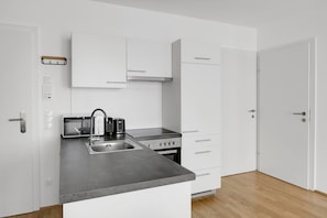Een moderne keuken met witte kasten, een roestvrijstalen spoelbak, een inbouwoven en een broodrooster.
