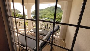 Een balkon met uitzicht op een bergachtig landschap en een wateroppervlak.
