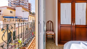 A balcony with a metal railing, a chair, and a wooden door with a lock. - A&n House of the Sun . (Torre del Mar)
