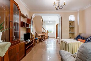 Relax in this inviting living space with a flat-screen TV, dining table, and comfortable sofa.