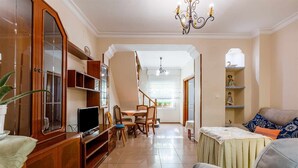 A living room with a dining area, wooden cabinets, a television, and a chandelier. - A&n House of the Sun . (Torre del Mar)