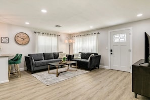 A living room with two sofas, a coffee table, a TV, and a clock on the wall.