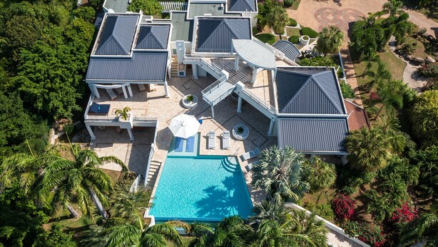 A large, modern house with multiple roof sections, a swimming pool, and lush surrounding greenery. - Les Palmiers Bleus | Ocean Front - Located in  Tropical Terres Basses with Private Pool (Saint Martin)
