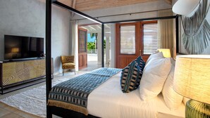 A modern bedroom with a large bed, a TV, and a view of the outdoors. - Les Palmiers Bleus | Ocean Front - Located in  Tropical Terres Basses with Private Pool (Saint Martin)