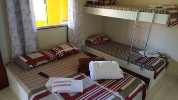 Un dormitorio con literas, una ventana con cortinas amarillas y un control remoto sobre la cama.