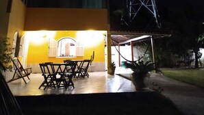 A house with a patio area, a dining table with chairs, and a tall metal tower in the background. - Guest house da torre (Sao Pedro da Aldeia)