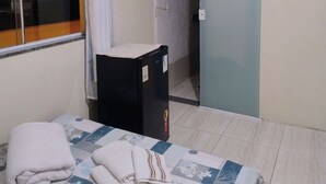 A hotel room with a bed, a small refrigerator, a television mounted on the wall, and a window with curtains. - Guest house da torre (Sao Pedro da Aldeia)