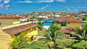 A residential area with houses, some with tiled roofs and others with flat roofs, surrounded by greenery and palm trees. - Guest house da torre (Sao Pedro da Aldeia)