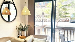Una sala de estar acogedora con un sofá, un reposapiés y un ventanal que ofrece vistas al exterior.