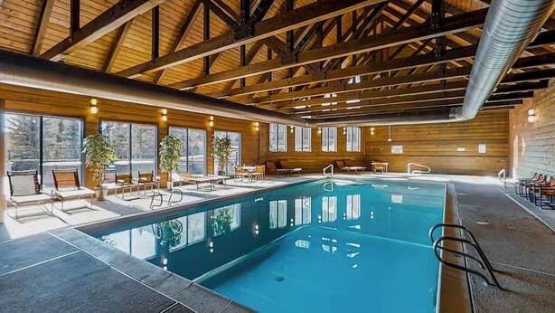 Una piscina interior con techo de madera y ventanas amplias.